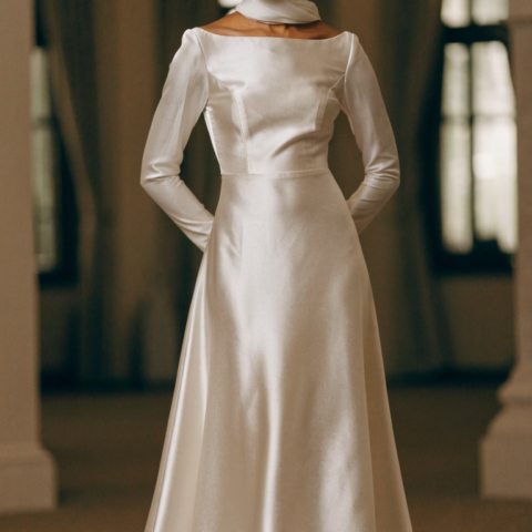 Bride in ivory satin A-line gown with bateau neckline and matching hijab in ballroom